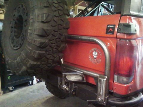 1989 Ford Bronco - Rear view of a 1989 Ford Bronco a custom tube swing-down tire carrier and a skull decal on the tailgate.