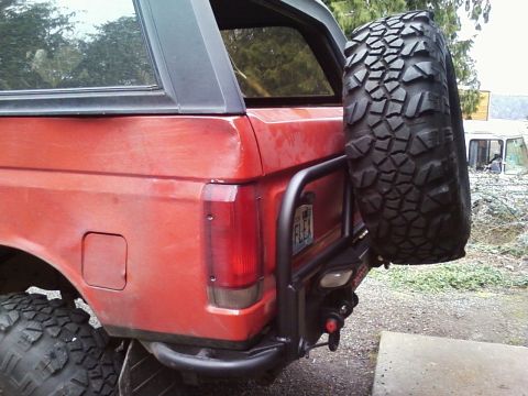 1989 Ford Bronco - This red SUV features a rear-mounted spare tire carrier and a custom bumper.