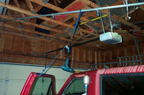 1995 Ford Bronco - Interior view of a red SUV in a garage, with a garage door opener and a blue hairdryer suspended overhead.