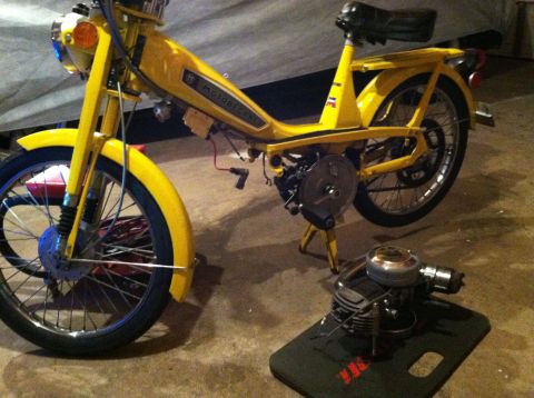 1981 Garelli Rally Sport - A yellow moped is parked next to its disassembled engine, which rests on a mat with a website logo.