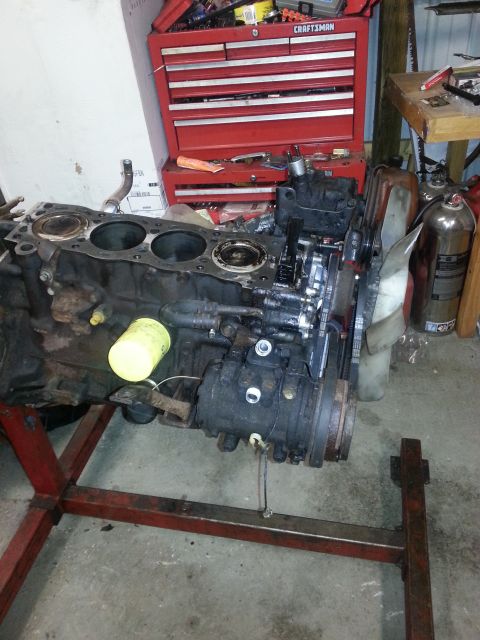 1987 Toyota 4Runner - Engine block assembly with oil filter and accessories, displayed on a red stand in a workshop setting.