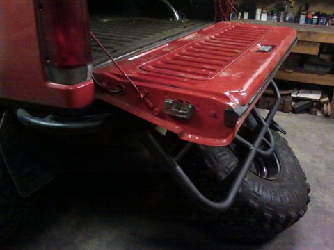 1989 Ford Bronco - Close-up of a red tailgate and a custom-mounted spare tire carrier.