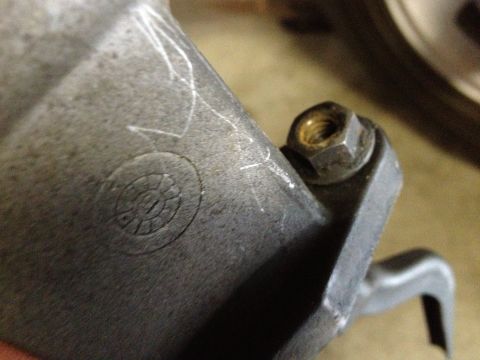 1978 Ford Bronco - This is a close-up of a metal automotive part, a bolt and nut and some visible scratch marks.