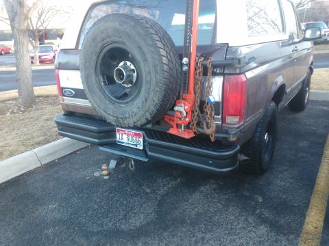 1992 Ford Bronco - Rear view of a brown 1992 Ford Bronco equipped with a spare tire, jack, and chains.