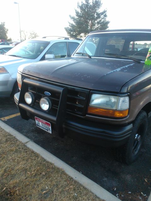 1992 Ford Bronco - A 1992 Ford Bronco is parked in a lot, showing its front grille and bumper with added lights.