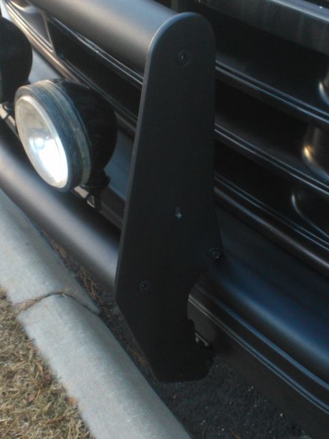1992 Ford Bronco - A black brush guard is mounted on the front of a vehicle, obscuring part of the grille and two auxiliary lights.