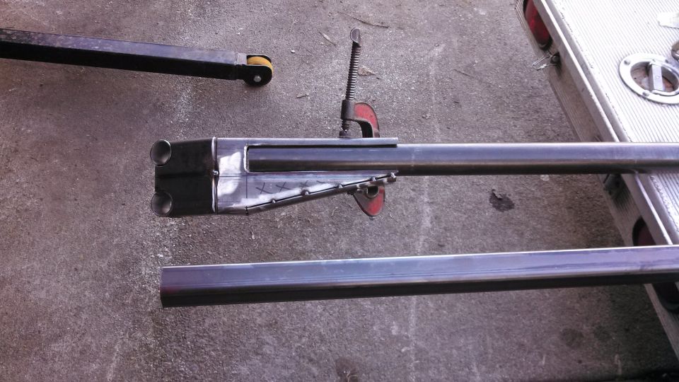 Metal tubes clamped together, with a double-barreled end, on a concrete surface