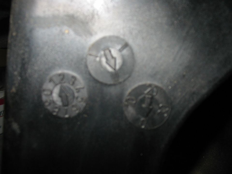 Close-up of a metal part with three circular indentations, one showing numbers 1, 2, and 3