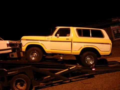 1979 Ford Bronco - A two-tone yellow and white Ford Bronco is loaded onto a trailer at night.