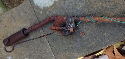 1978 Ford Bronco - A heavily rusted metal pipe assembly with attached wires rests on a concrete surface.