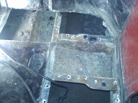 1978 Ford Bronco - Close-up view of a heavily rusted and damaged vehicle floor pan, showing signs of repair.