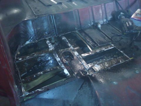 1978 Ford Bronco - The floor pan of a vehicle is visible, with sections cut out and treated for rust.