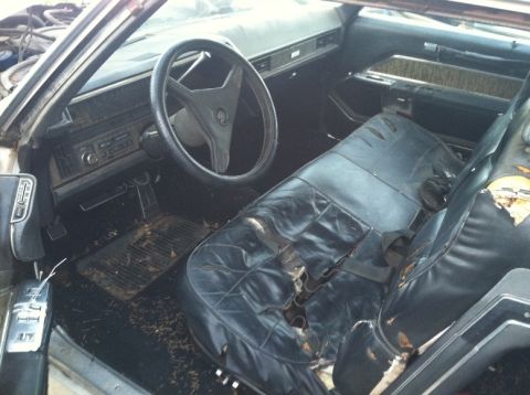1970 Cadillac DeVille - The interior of an old Cadillac shows significant wear and tear on the seats and dashboard.