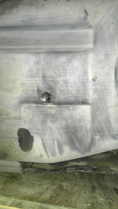 1982 Jeep Wagoneer - Close-up view of a vehicle's fuel tank underside, showing a small leak and general wear.