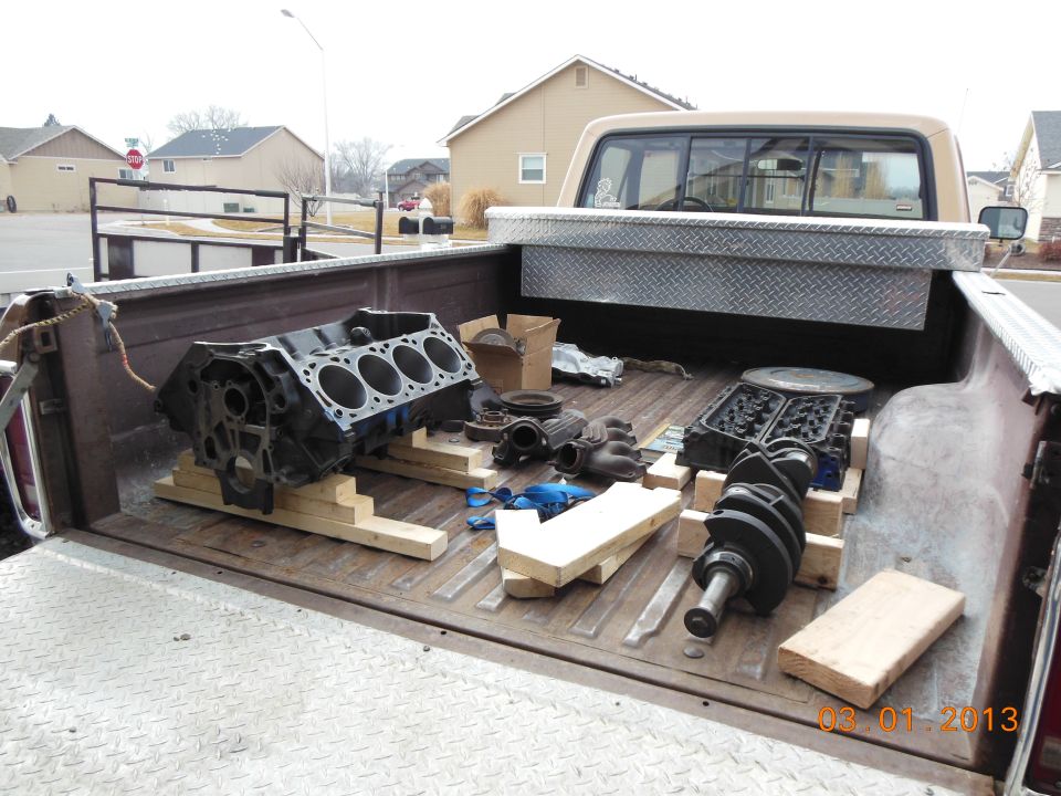 Disassembled V8 engine block and parts laid out in pickup truck bed