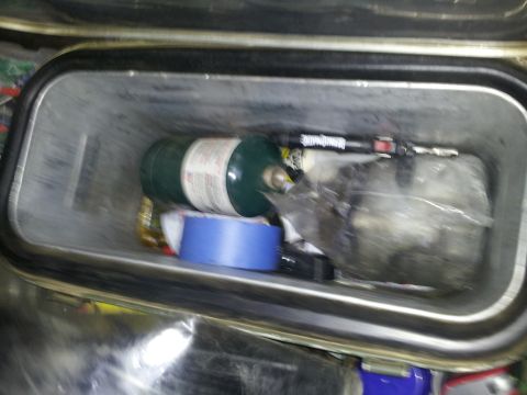 1986 Ford Bronco - Storage bin contains a propane tank, tape, and other miscellaneous items.