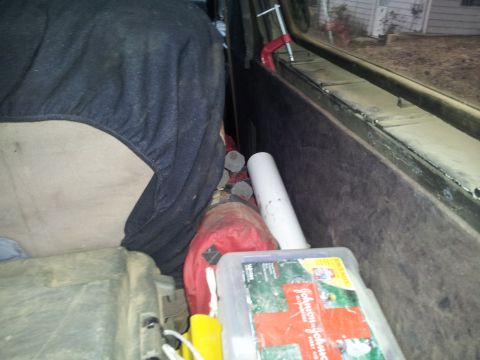 1986 Ford Bronco - The cargo area of a vehicle is filled with various items, including a first aid kit and a red bag.