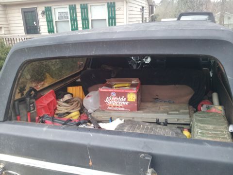 1986 Ford Bronco - Cargo area of a truck filled with supplies, including a box of Fireside Supreme and tools.