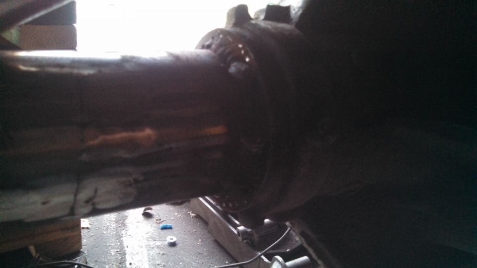 Close-up of a rusty metal tube with welds, part of a vehicle's undercarriage