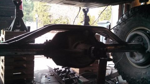 1967 Ford F-250 - Close-up view of a vehicle's rear axle assembly, supported by jack stands and custom suspension modifications.