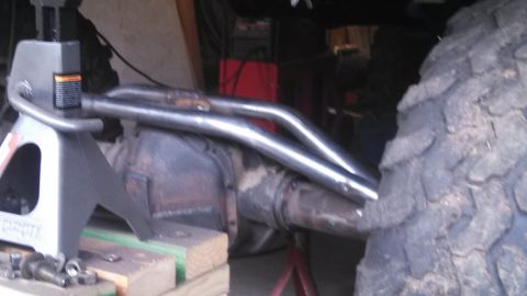 1967 Ford F-250 - Custom dual exhaust pipes are installed on the rear axle of a vehicle, which is raised on jack stands.