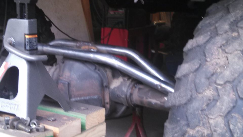 Dual exhaust pipes over rear axle, supported by jack stands