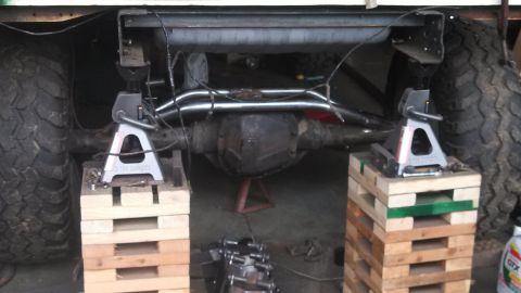 1967 Ford F-250 - Truck's rear axle and exhaust system are elevated on jack stands and wood blocks for maintenance.