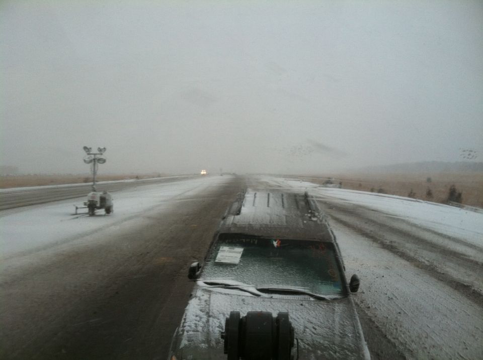 SUV driving on a snowy road with a portable light tower on the side