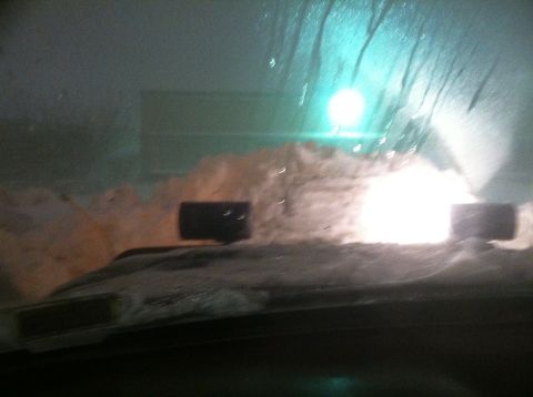 1989 Ford Bronco - View from inside a vehicle during a snowstorm, with headlights illuminating the snow.