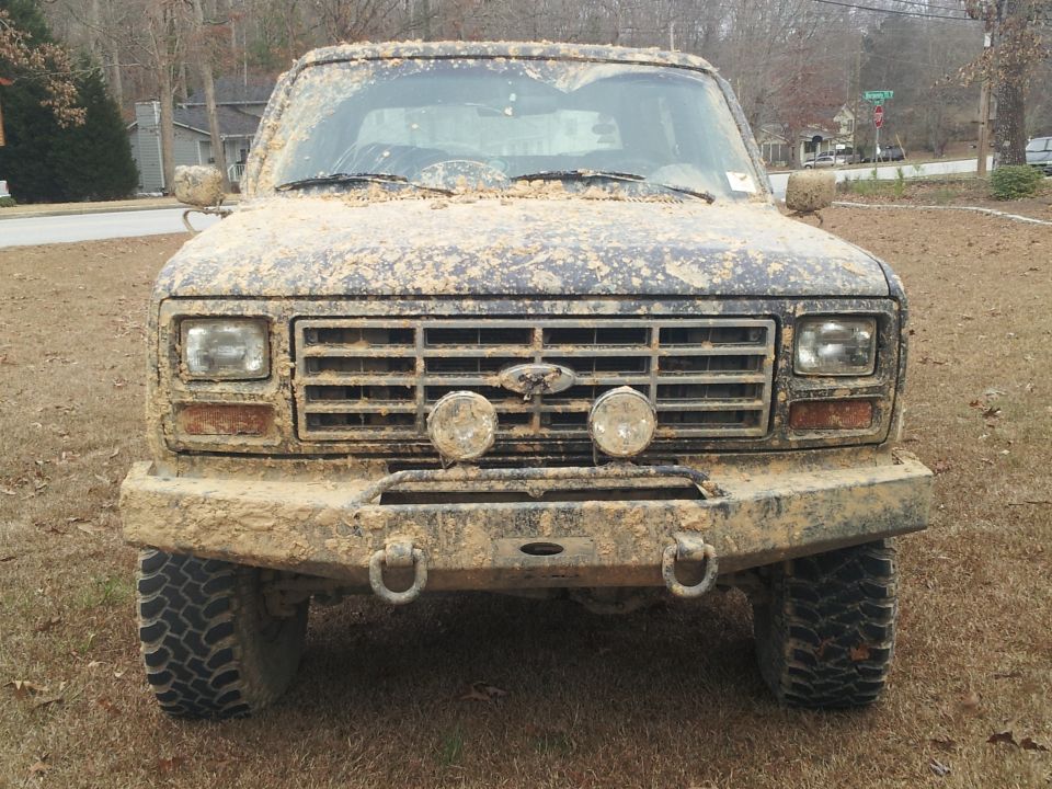 Mud-covered 1986 Ford Bronco front view with aftermarket bumper and lights