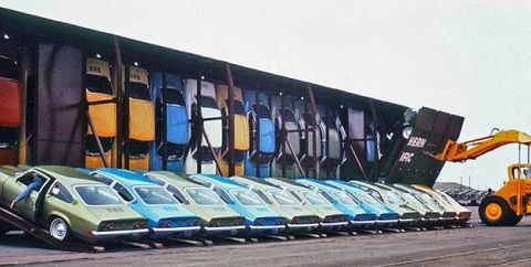 1969 Ford Torino - Cars are being loaded onto a train car using a front loader, with many vehicles lined up.