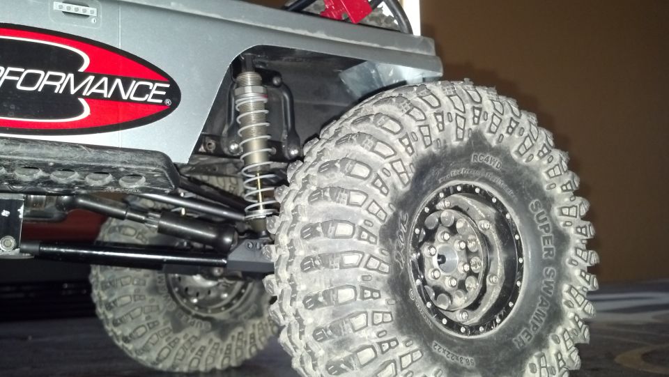 Close-up of a Super Swamper tire on an RC rock crawler, showing suspension components and a 'Performance' sticker