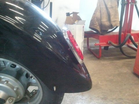 1995 Ford F-150 - Close-up of a vehicle's rear fender and taillight assembly, showing part of the wheel and surrounding workshop environment.