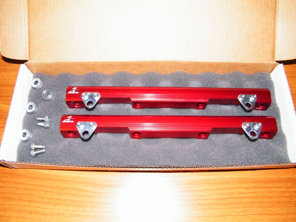Pair of red aluminum fuel rails with hardware in a box