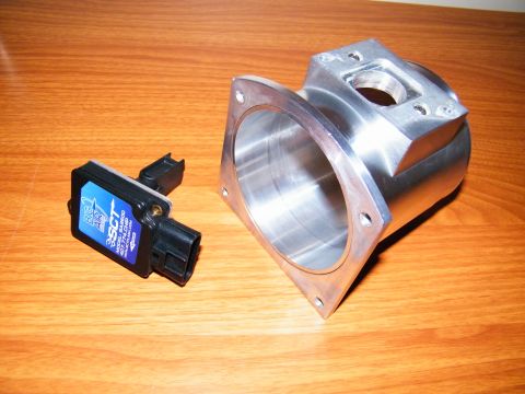 2004 Ford Crown Victoria - A blue SCT MAF sensor and a custom aluminum intake manifold adapter are displayed on a wooden table.