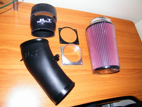 2004 Ford Crown Victoria - JLT Performance cold air intake kit includes a black intake tube, silicone coupler, and a red JLT high-flow air filter.