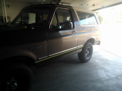1992 Ford Bronco - This Ford Bronco is parked inside a garage, showing its two-tone paint and side trim.