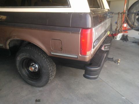 1992 Ford Bronco - The rear of a brown and white 1992 Ford Bronco is shown with a spare tire mounted on a swing-away carrier.