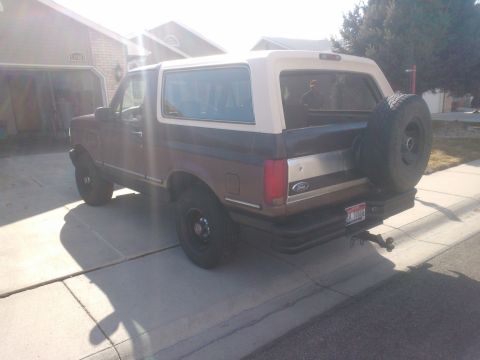 1992 Ford Bronco - This 1992 Ford Bronco is shown in a 3/4 rear view, its distinctive brown and white paint scheme and a spare tire mounted on the tailgate.