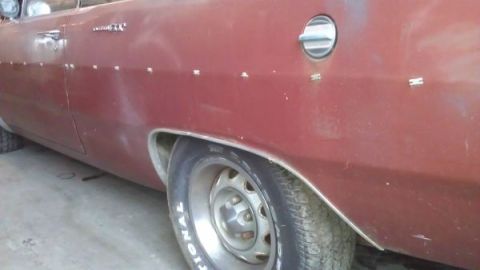 1988 Ford Bronco - Close-up of a red car's side panel, showing the wheel well and a fuel filler cap.