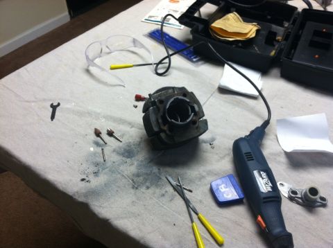 1981 Garelli Rally Sport - Workbench setup with engine cylinder, rotary tool, and safety glasses for repair or modification.