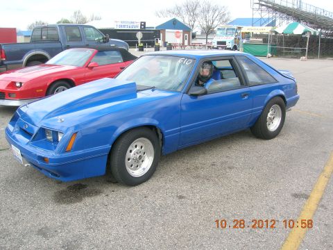 2003 Ford Crown Victoria - A blue Ford Mustang hatchback is parked at a drag strip with other vehicles visible.