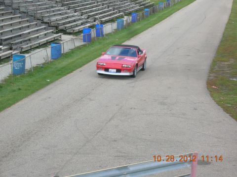 2003 Ford Crown Victoria - A red convertible sports car is seen on a race track with bleachers in the background.