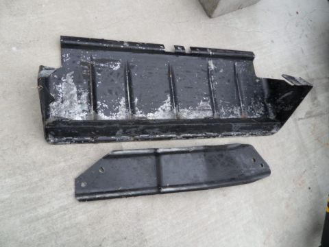 1994 Jeep Cherokee - Two black metal underbody skid plates are shown on a concrete surface.