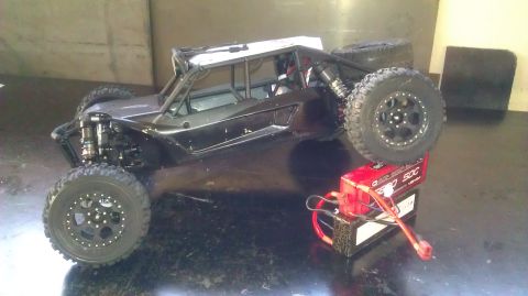 1996 Ford Bronco - RC rock crawler buggy sits next to a red LiPo battery pack.