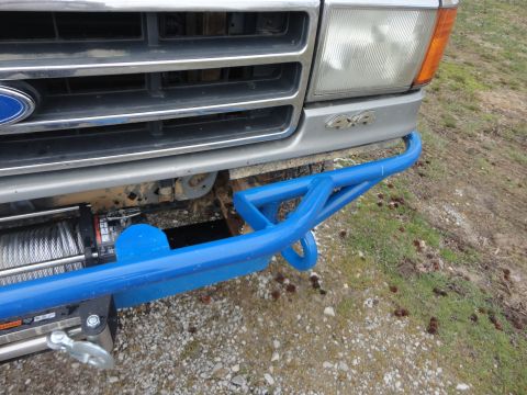 1990 Ford Bronco - Front view of a Ford Bronco with a custom blue bumper and winch, showing the grille and headlights.