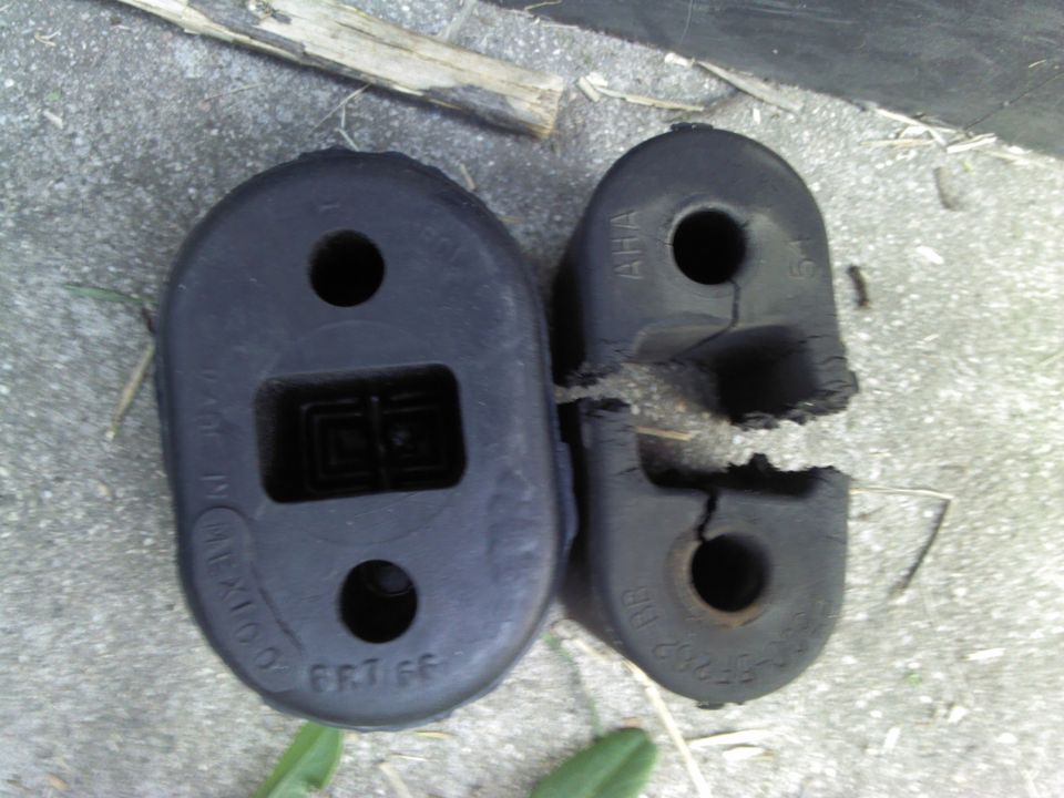 Two rubber exhaust hanger isolators on concrete, one split and cracked