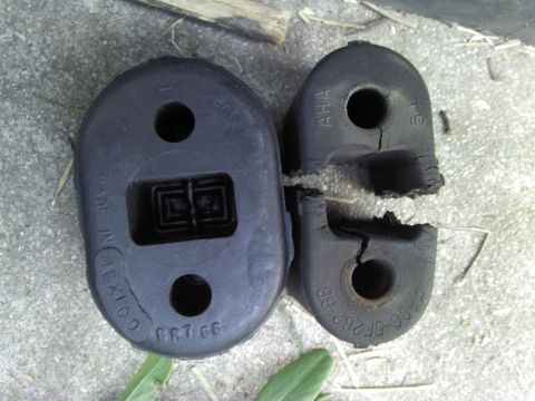 2000 Lincoln Continental - Two rubber exhaust hangers, one showing significant damage and cracking, lie on a textured surface.