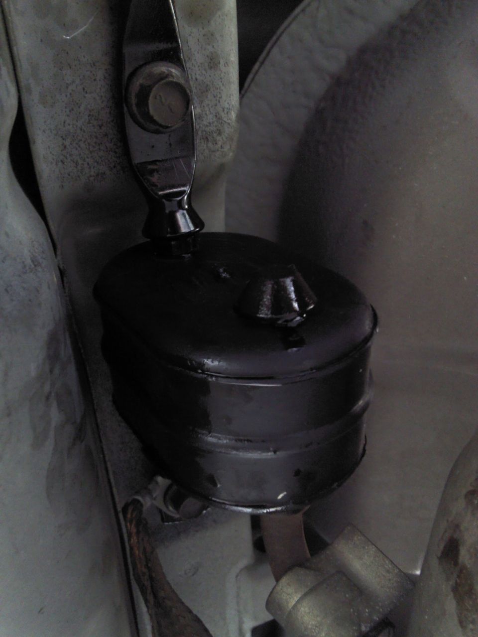 Close-up of a black rubber suspension part bolted to a metal bracket