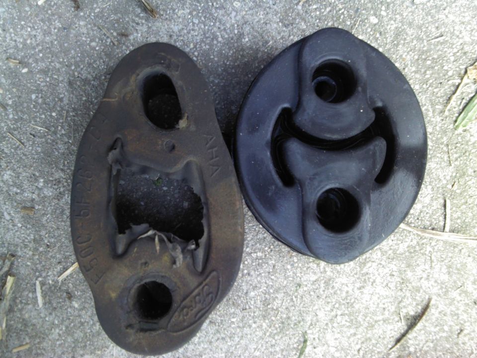 Two rubber exhaust hangers, one old and damaged with Ford logo, the other new